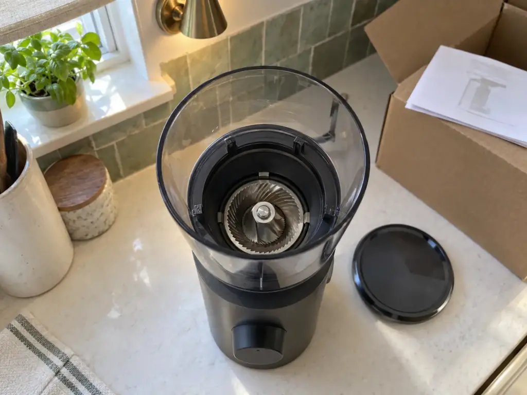 Looking down into the empty hopper of a new cheap burr grinder to see the conical burr before the first grind
